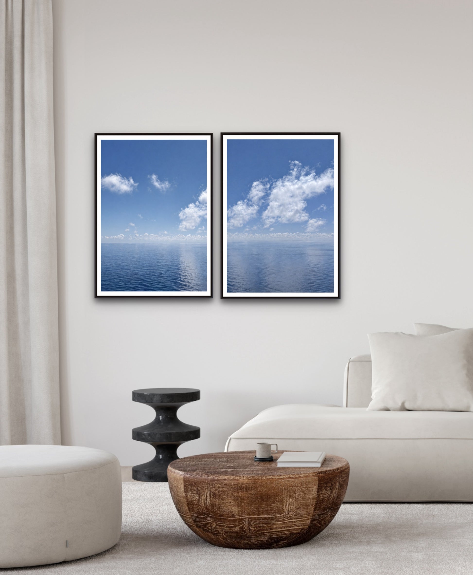 Two framed blue sky and cloud prints on a wall above a sofa in a living room.