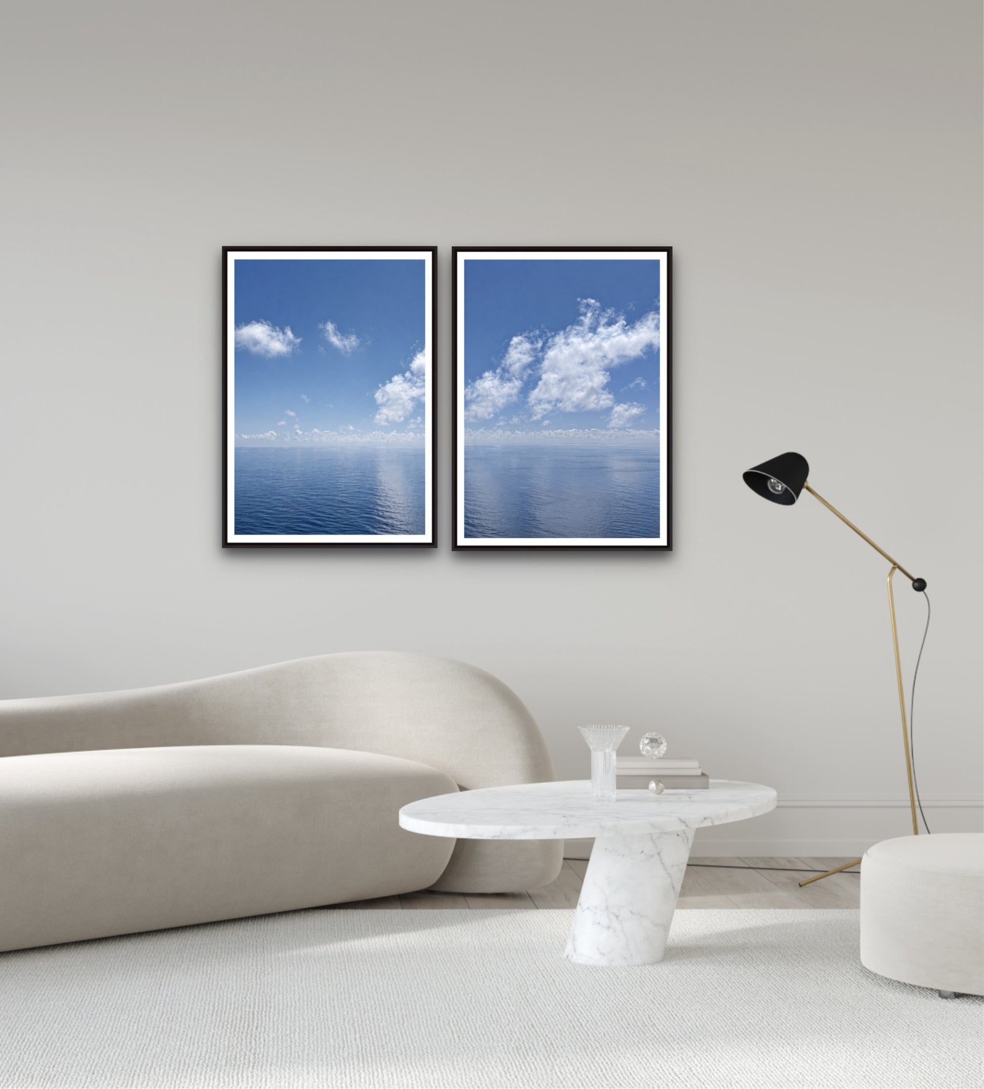 Two framed pictures of blue skies with clouds on a wall above a sofa.