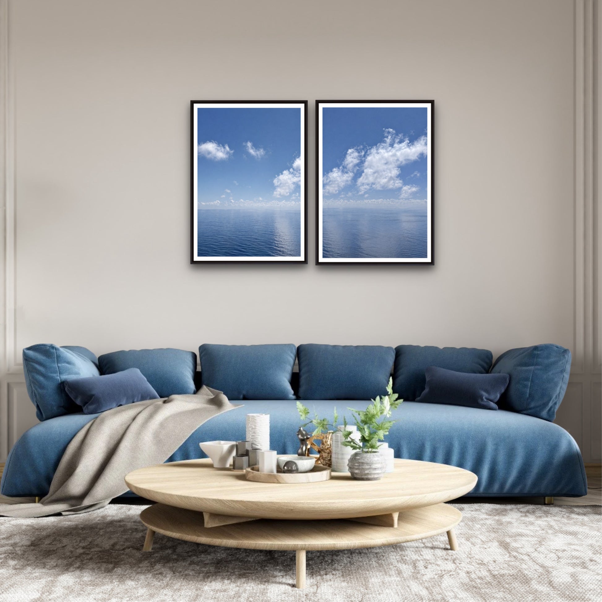 Modern living room with a blue sofa, wooden coffee table, and two framed pictures of the ocean.