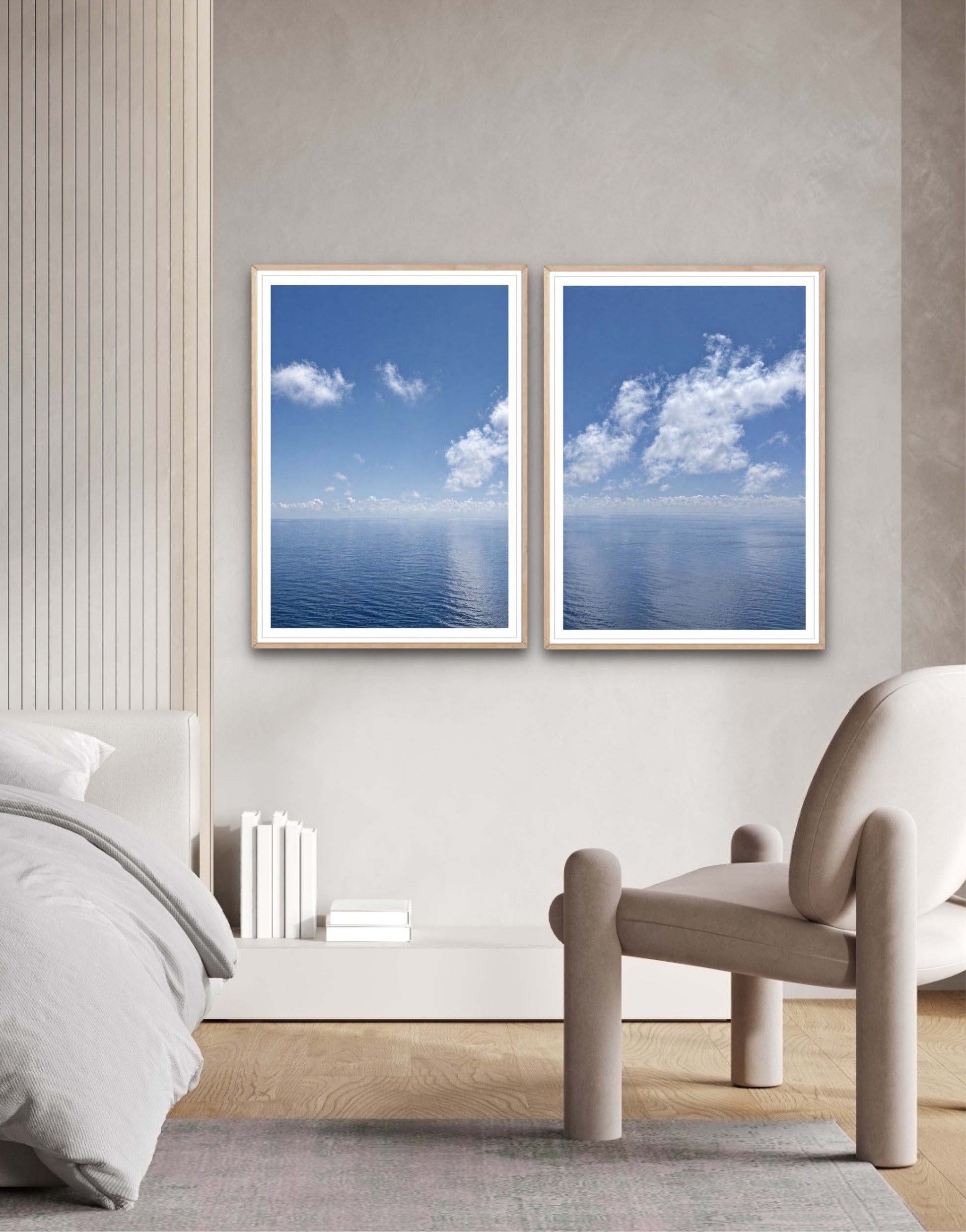 Two framed pictures of blue skies with clouds on a wall above a bed.