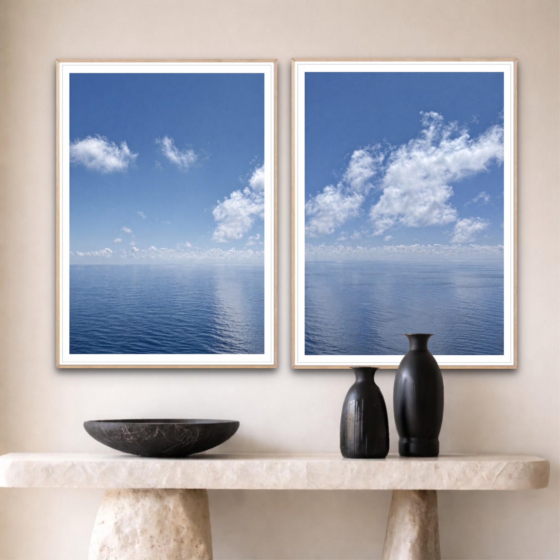 Two framed pictures of a blue sky with clouds on a wall above a console table.