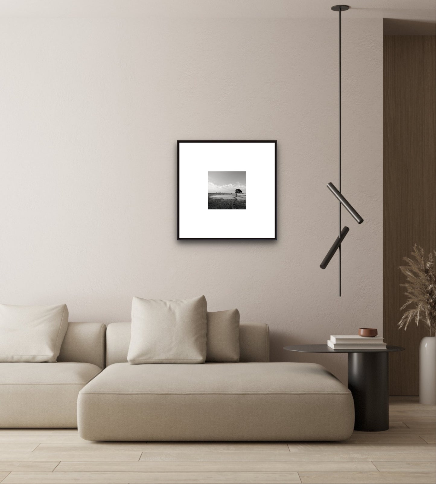 Modern living room with a beige sofa, framed artwork, and pendant light.