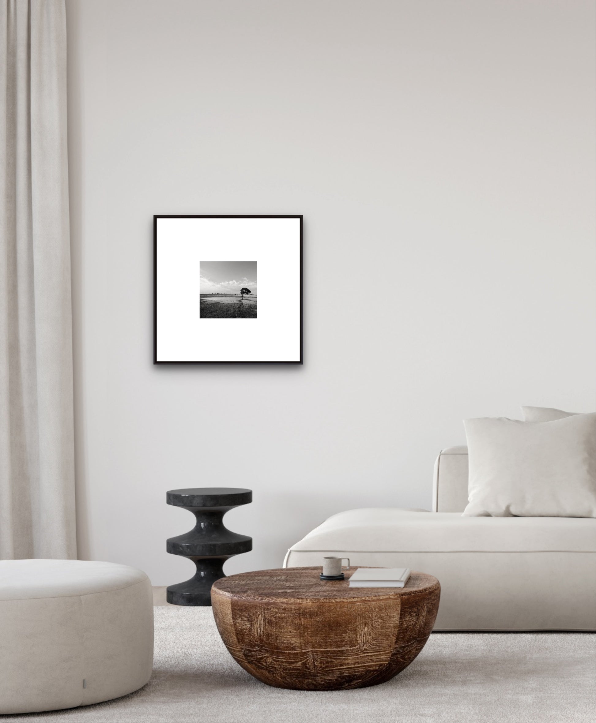 Framed black and white artwork on a wall above a wooden coffee table in a living room.