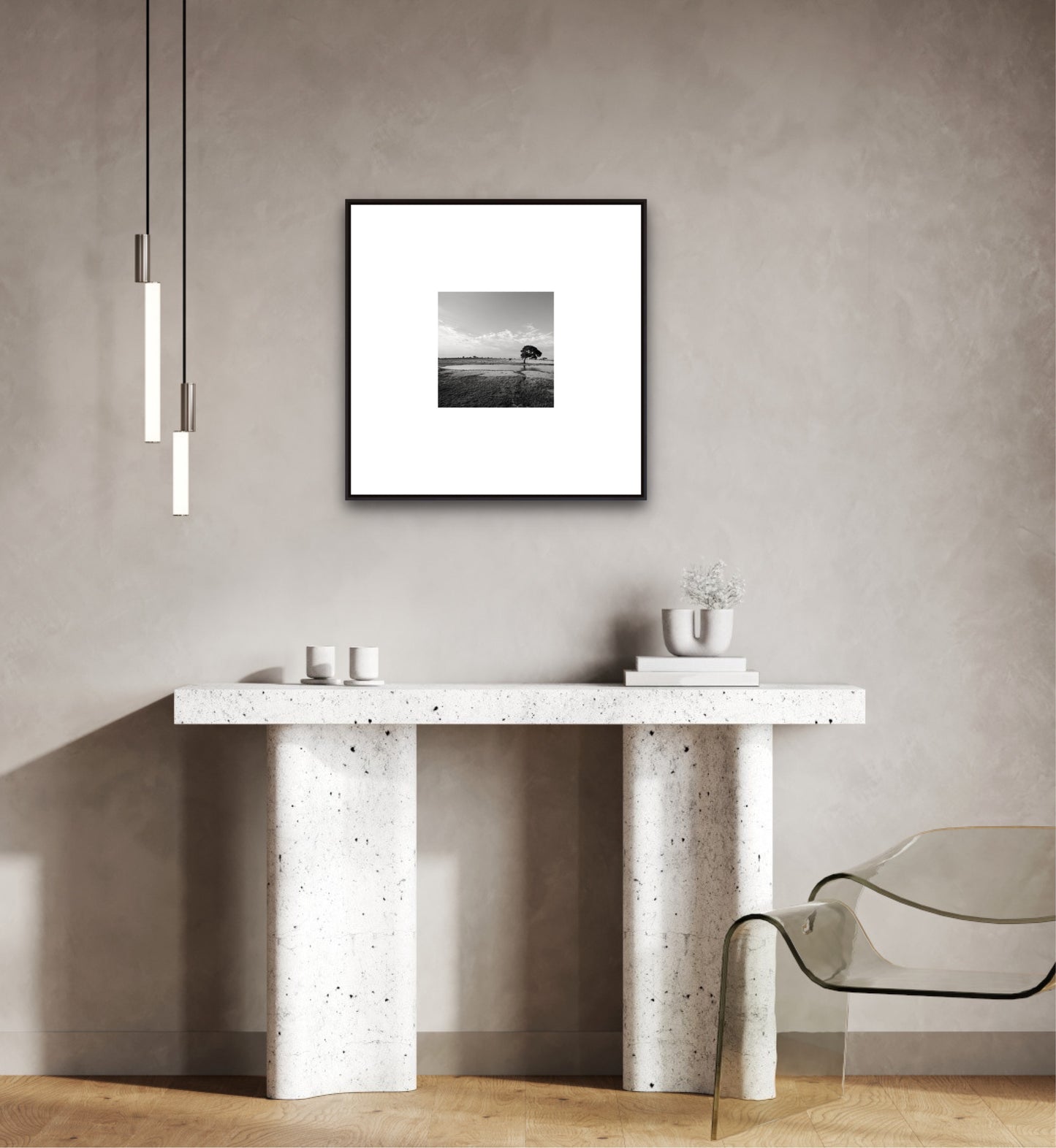 Modern interior with a concrete console table, glass chair, and framed black and white photo on the wall.
