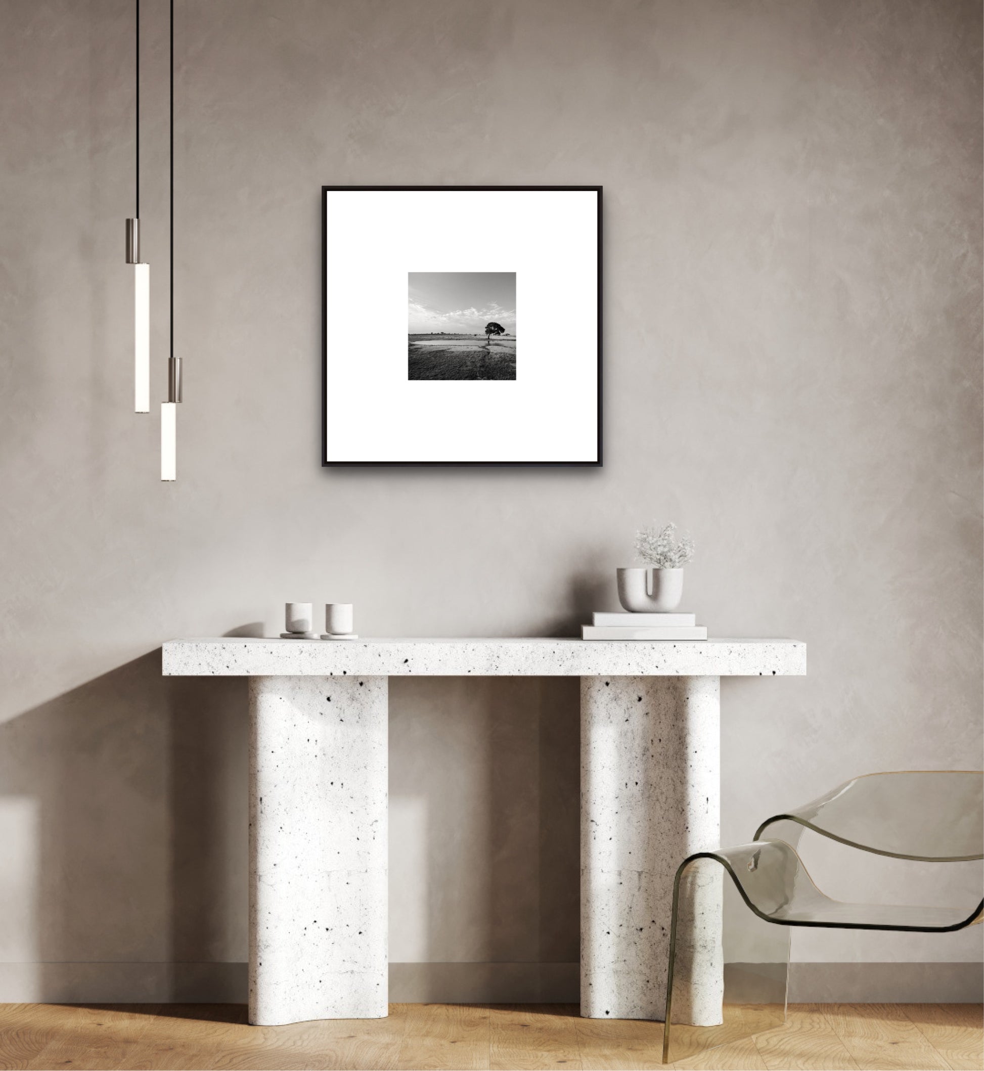 Modern interior with a concrete console table, glass chair, and framed black and white photo on the wall.